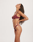 Woman wearing a burgundy bikini against a white background