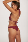 Woman wearing a burgundy bikini against a white background