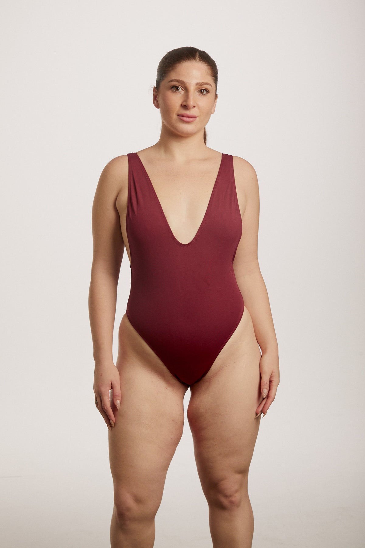 Woman wearing a burgundy swimsuit against a plain background