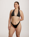 Woman wearing a black bikini against a plain background