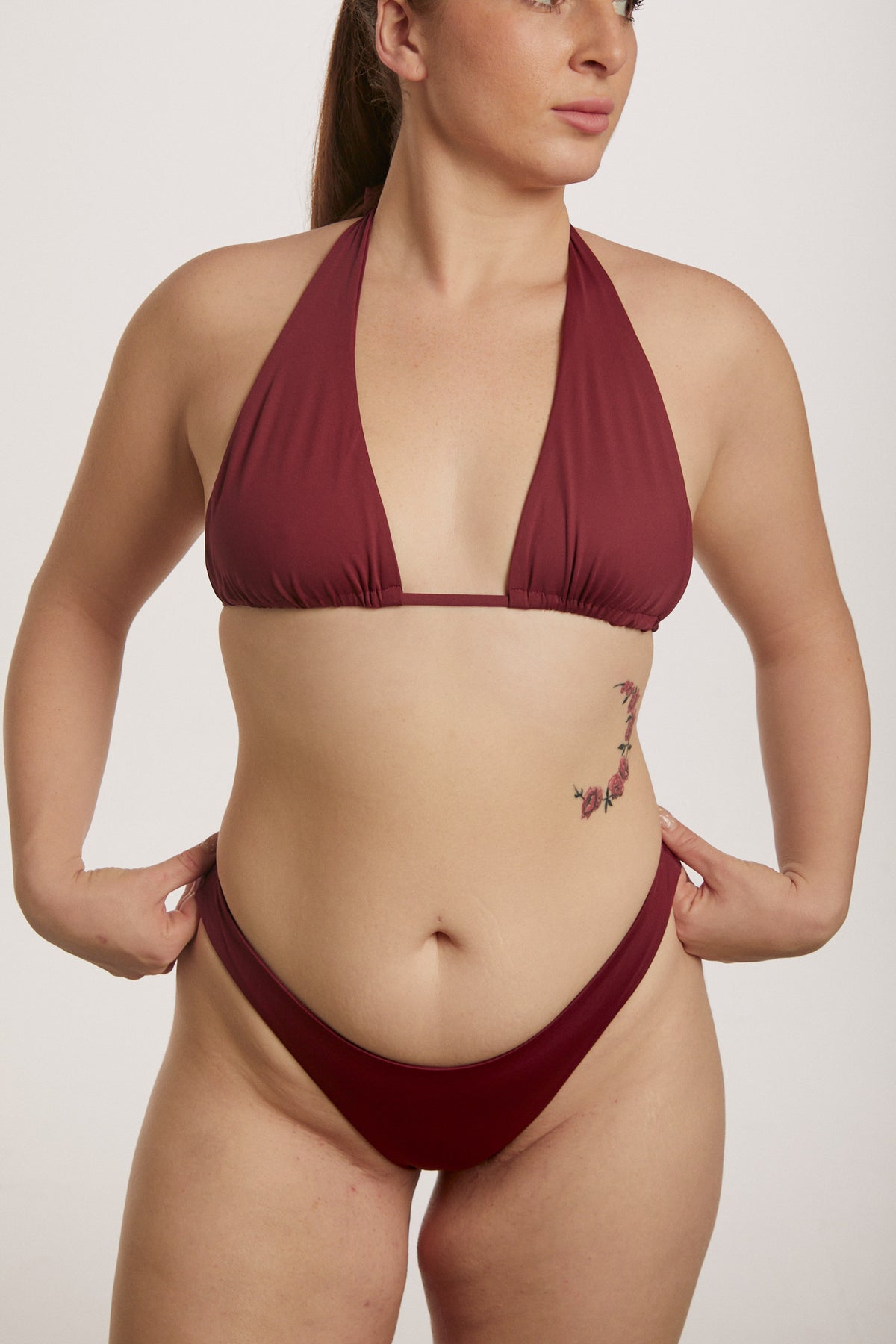 Woman wearing a burgundy bikini against a plain background